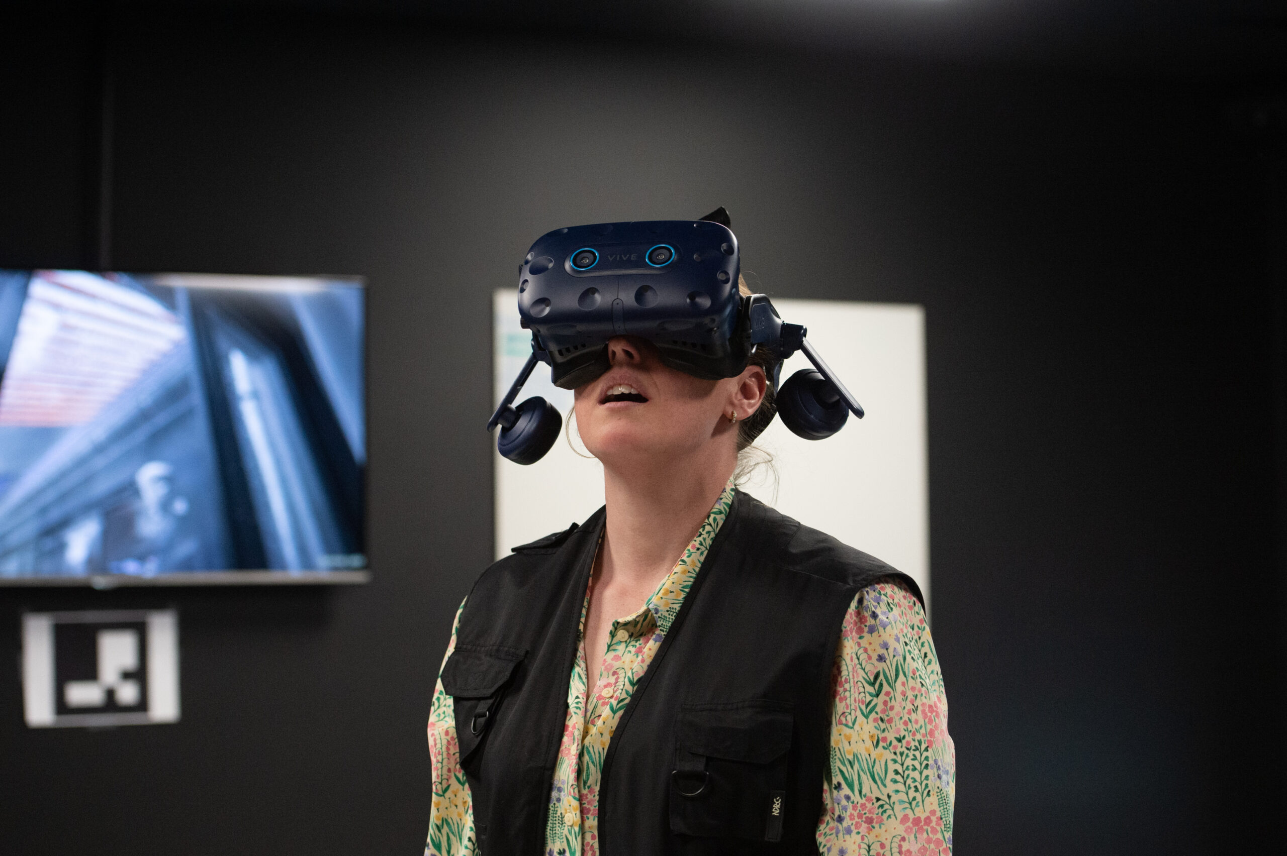 Kvinna står i mörkt rum med VR-glasögon.